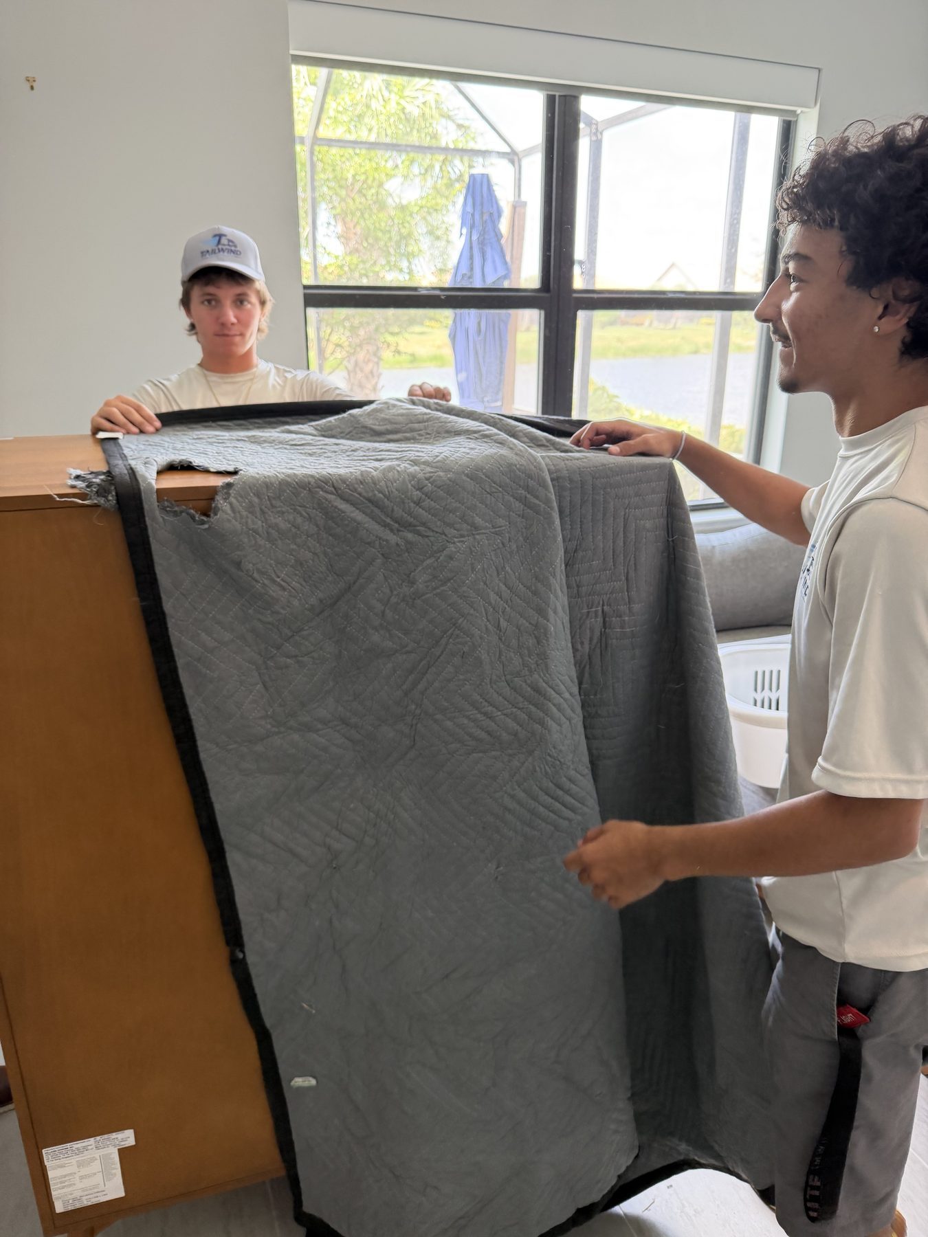 Two Tailwind Movers crew members wrapping a dresser together on a job