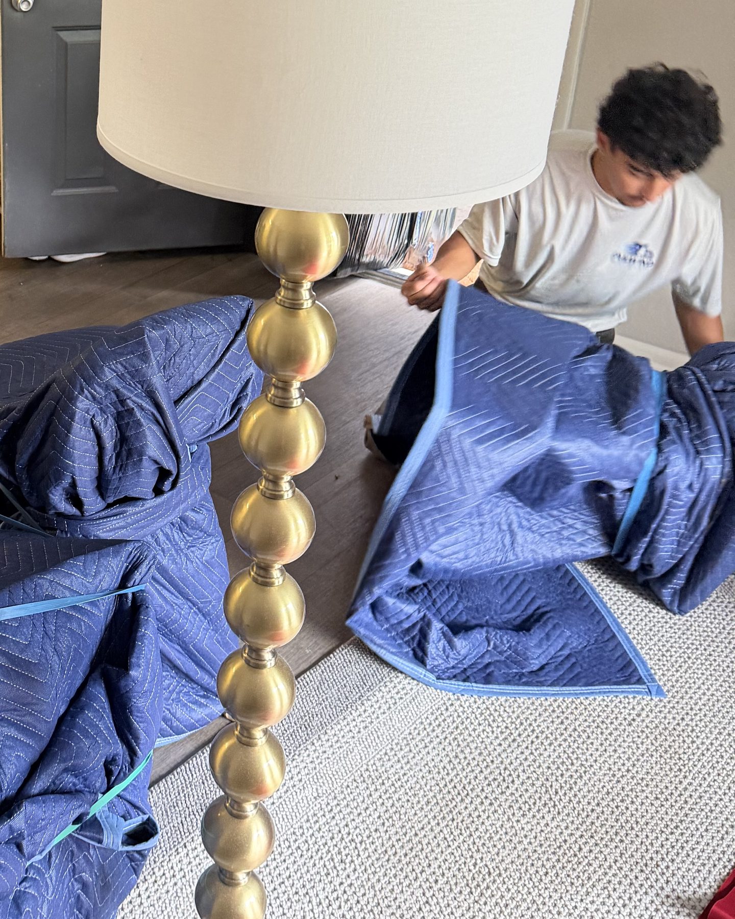 Tailwind Movers crew member carefully wrapping furniture and a lamp in moving blankets on a Tampa Bay job