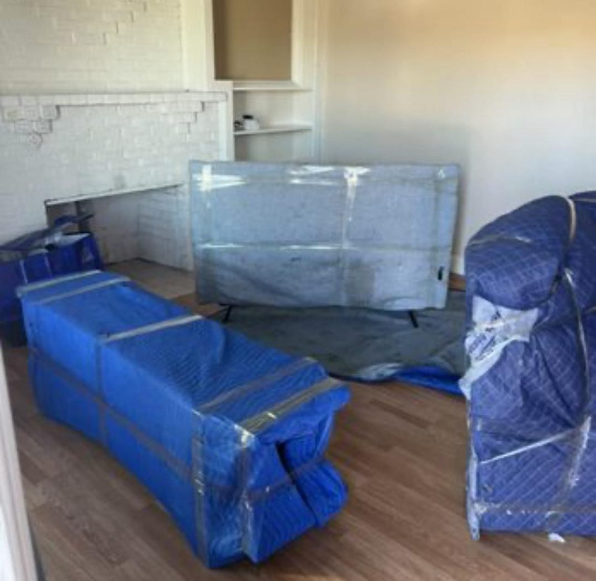 A living room with a sofa and TV wrapped and staged for a move